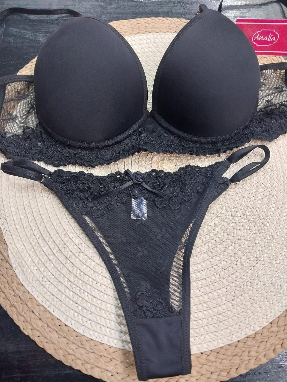 Conjunto de sujetador negro y tanga a juego sobre tapete tejido.