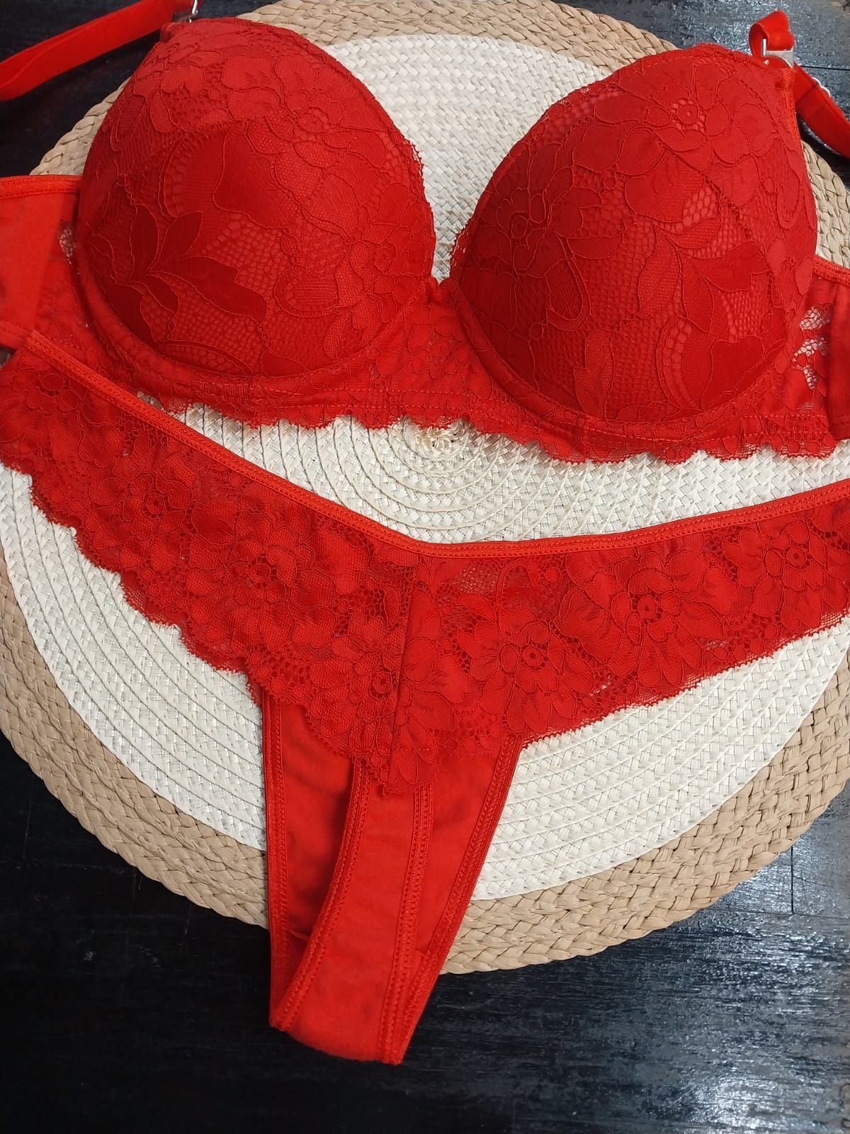 Conjunto de sujetador de encaje rojo y tanga a juego sobre una alfombra redonda tejida.