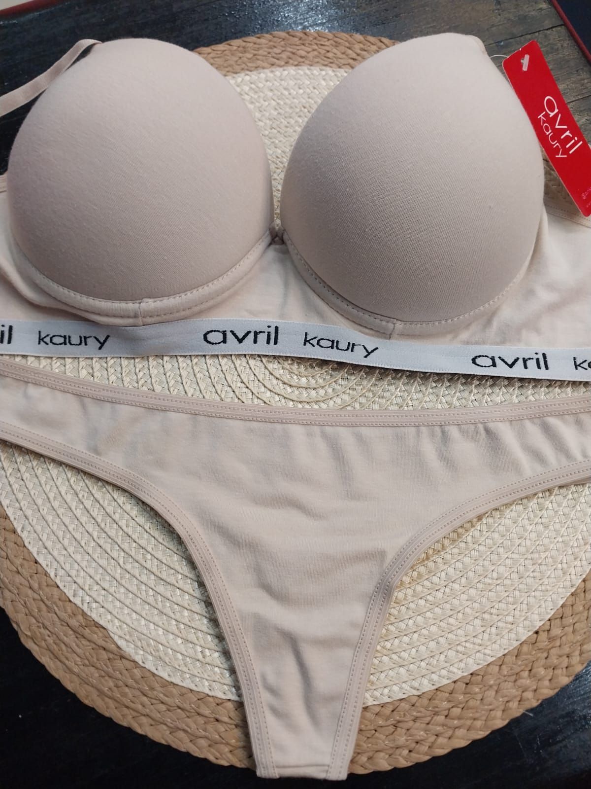 Conjunto de lencería beige, compuesto por sujetador con relleno y tanga, expuesto sobre una alfombra tejida.