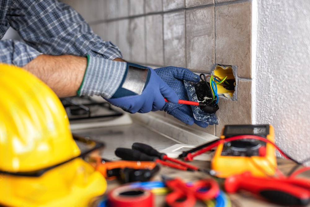 a man with a hard hat on side is working on an electrical outlet