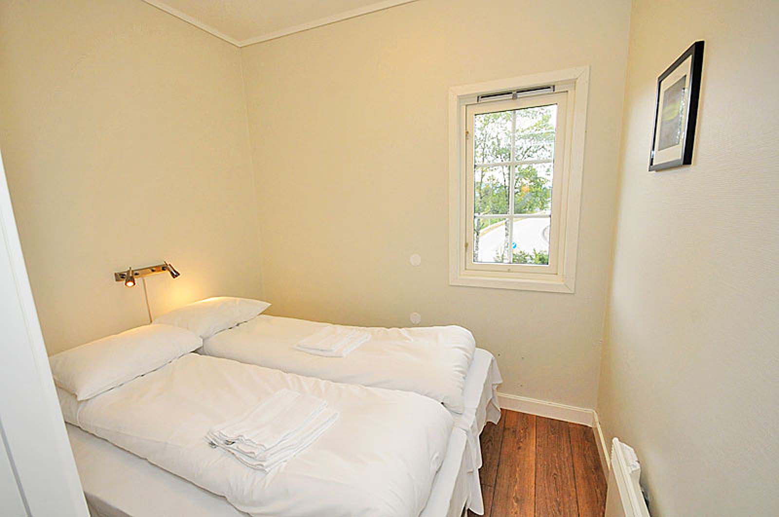 Et lite soverom med to senger og et vindu.