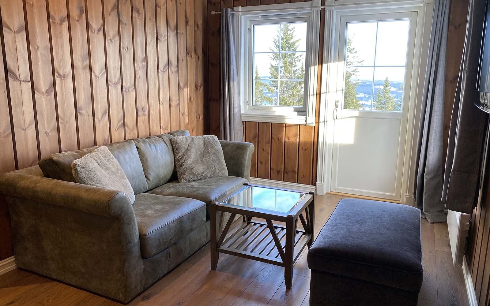 En stue med en sofa , salongbord , ottoman og TV.