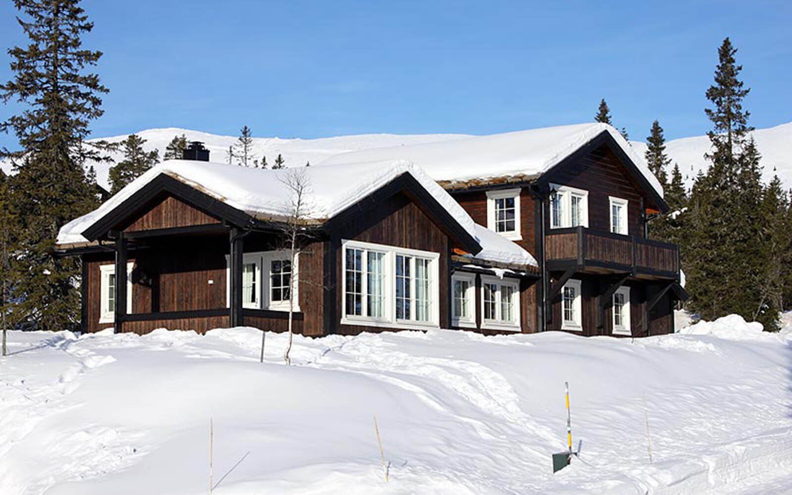 Et stort hus er dekket av snø på fjellet.