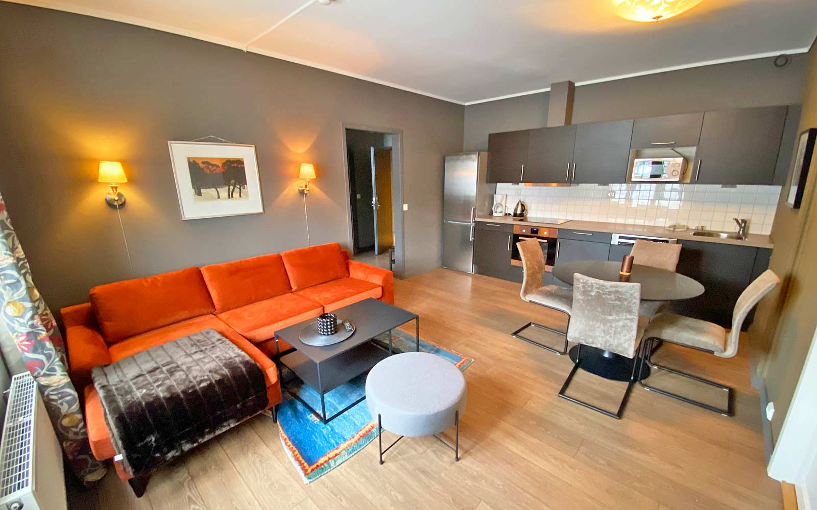 En stue med sofa , bord , stoler og kjøkken.