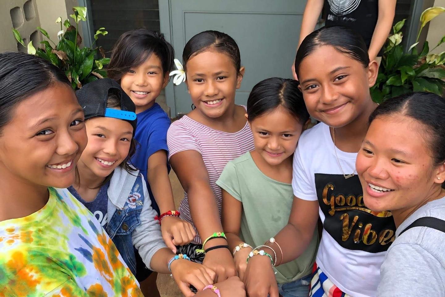 A group of young girls are posing for a picture and one girl is wearing a shirt that says good vibe.