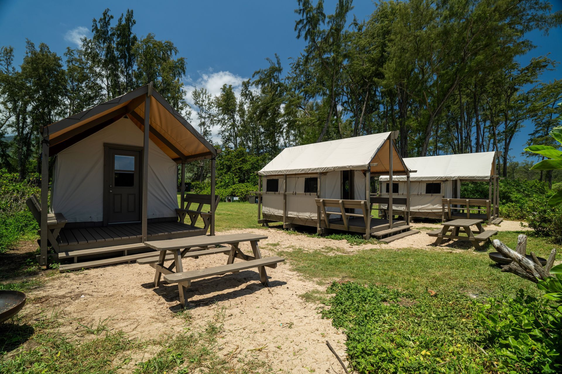 A tent with a porch and a picnic table in front of it.