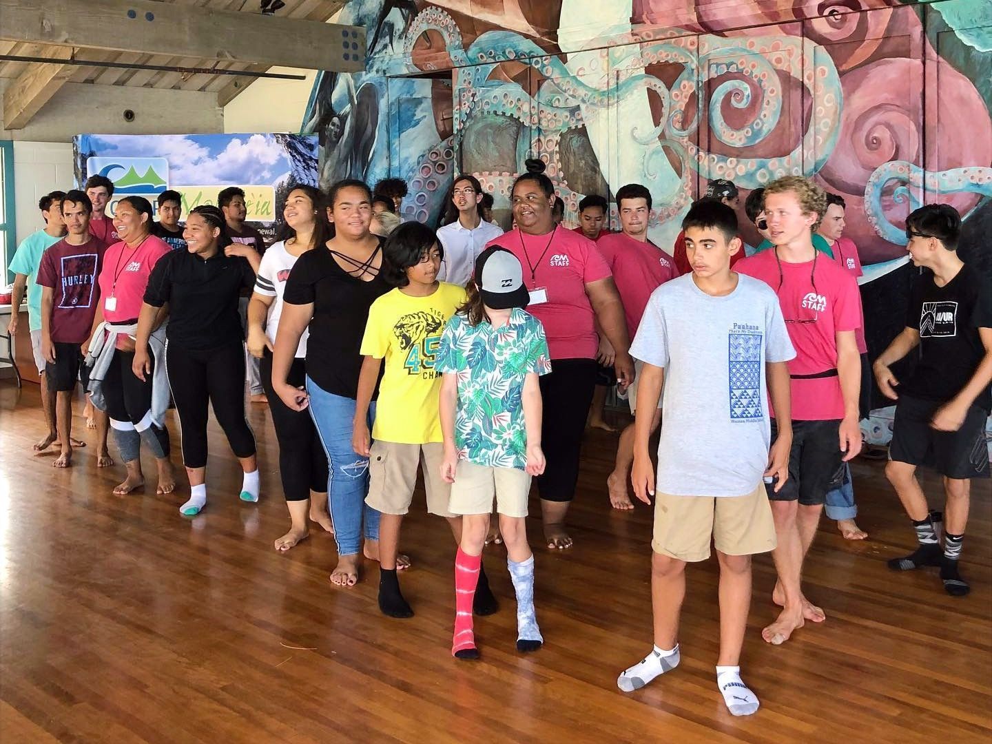 A group of people are standing in a room with a mural on the wall