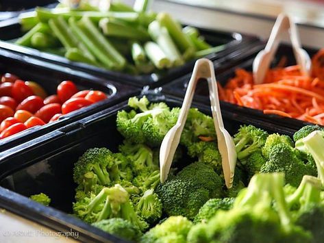 A buffet filled with broccoli , carrots , celery , tomatoes and other vegetables.