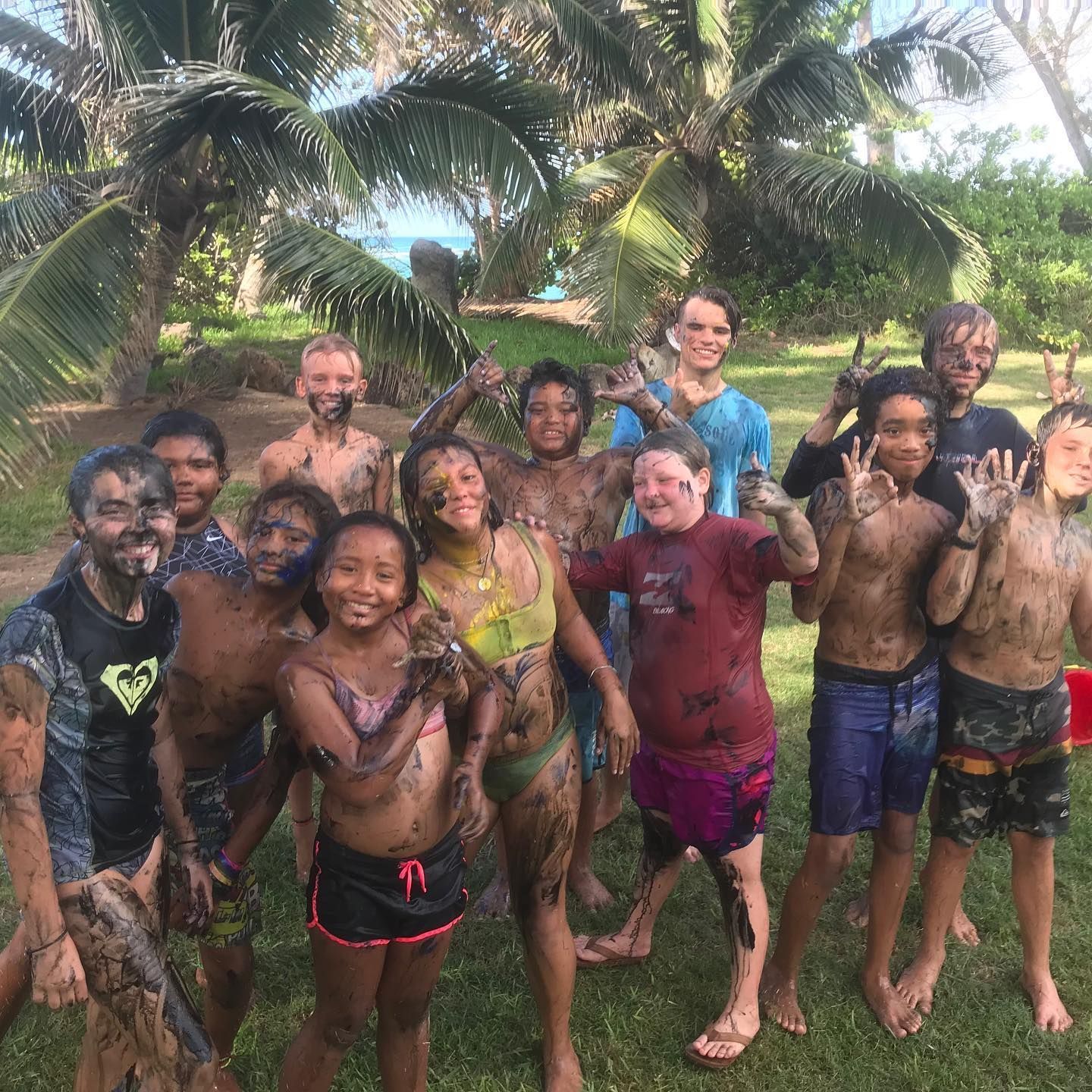 A group of children covered in mud are posing for a picture.