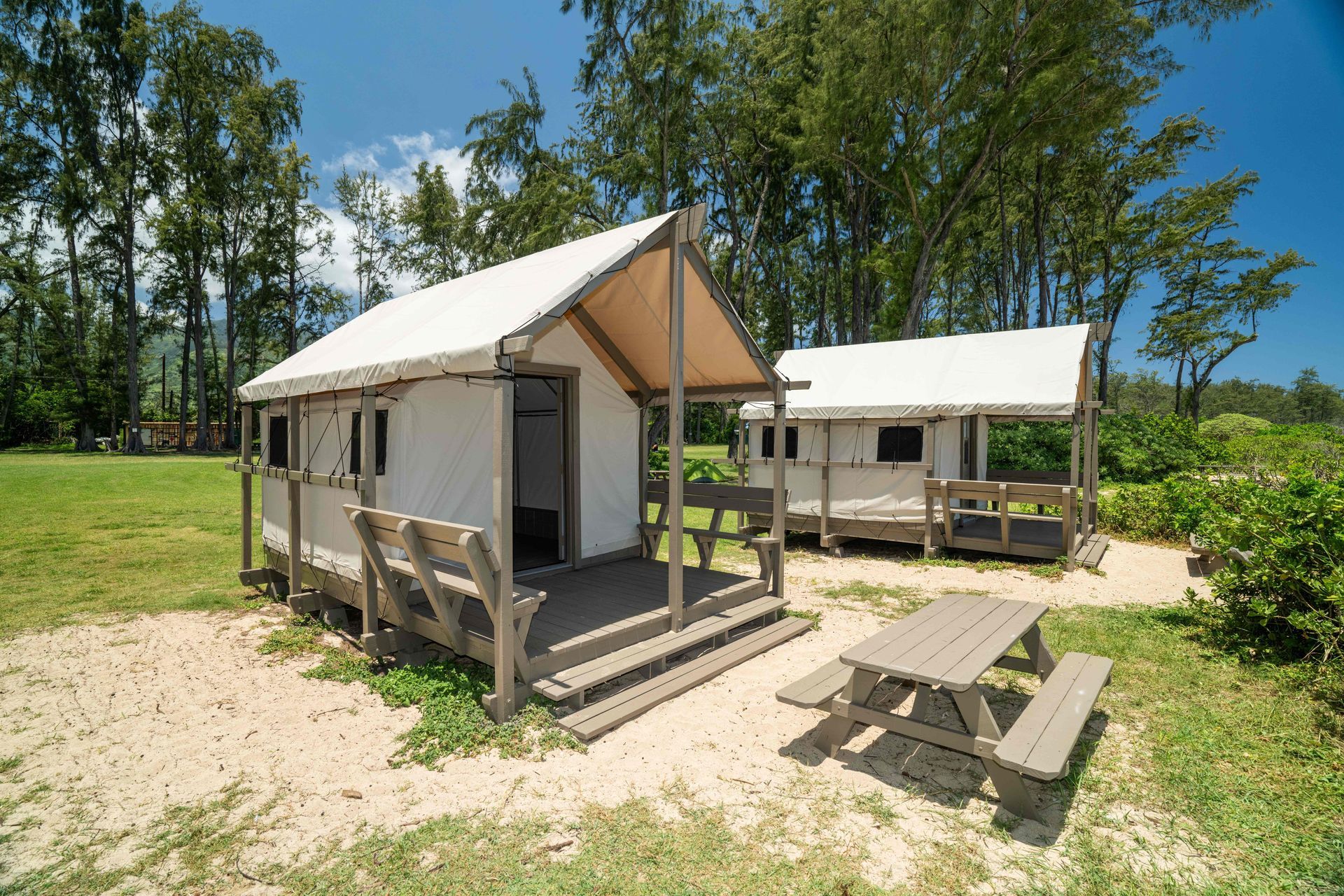 A small white tent with a picnic table in front of it.