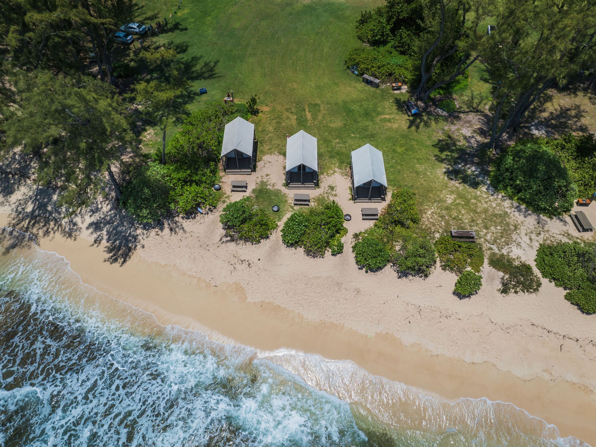 An aerial view of a beach with a few huts on it