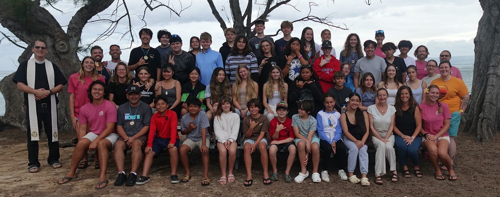 A large group of people are posing for a picture under a tree.