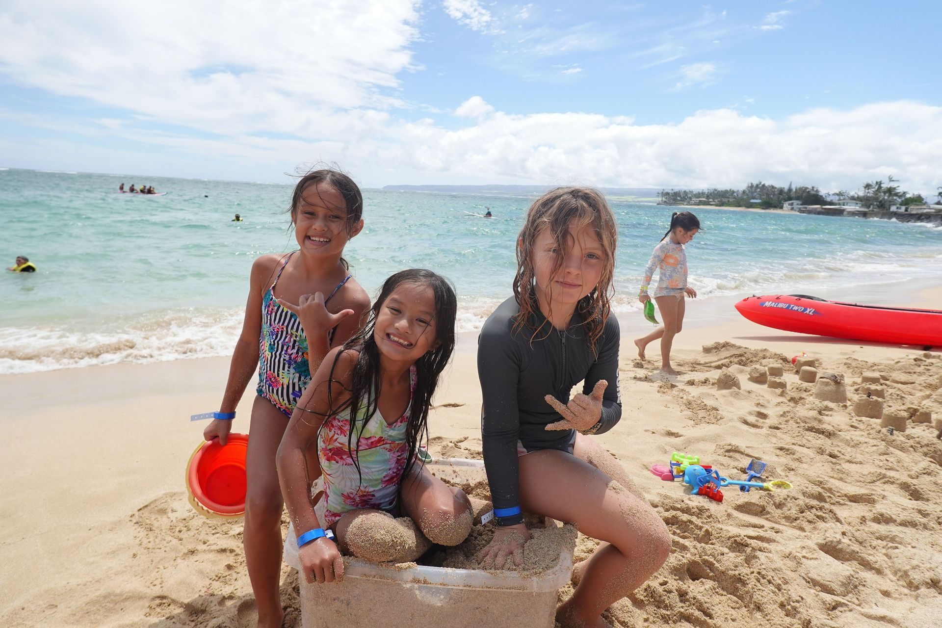 Three young girls are posing for a picture on the beach.