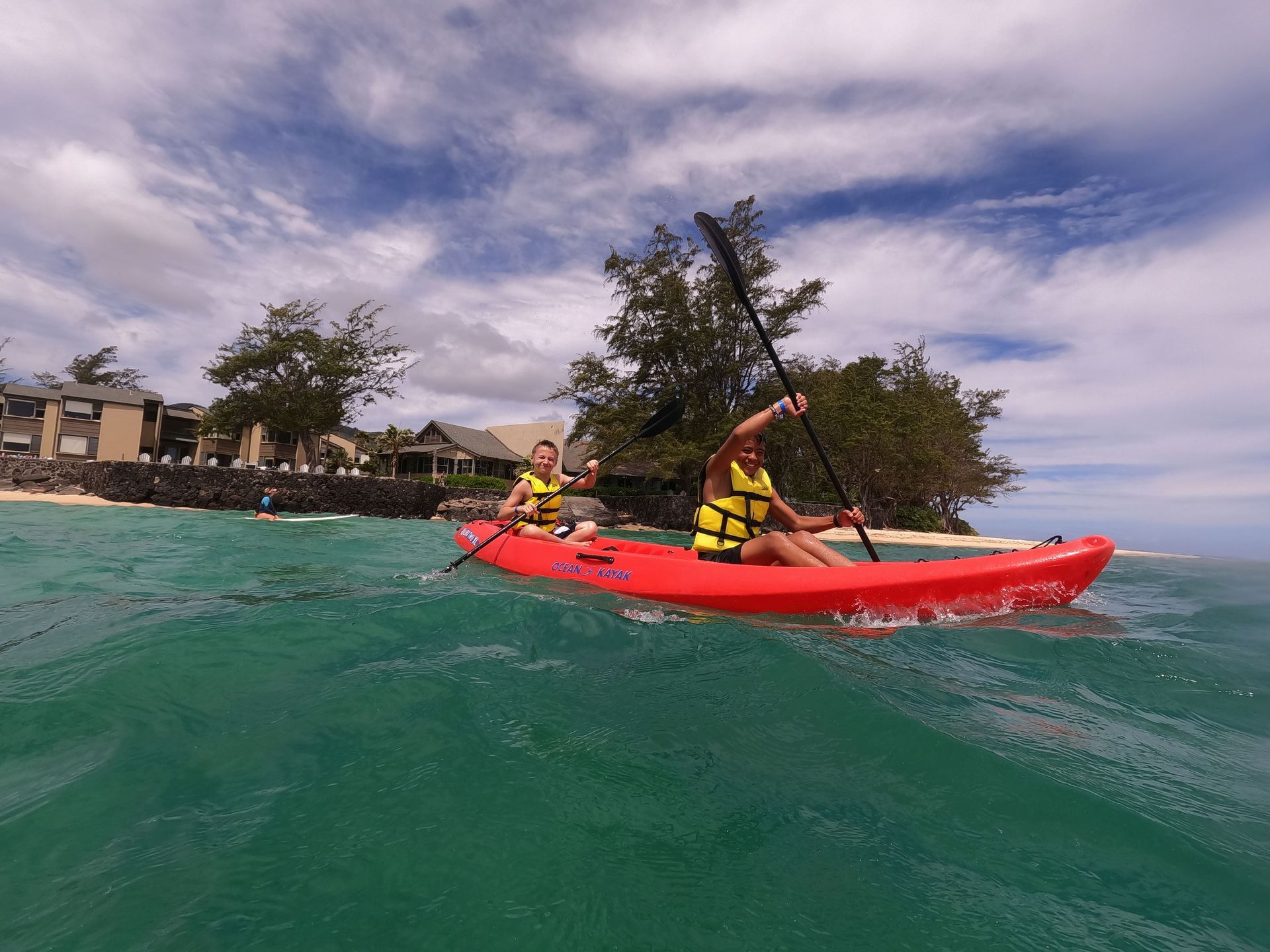 Two people are paddling a red kayak in the ocean.