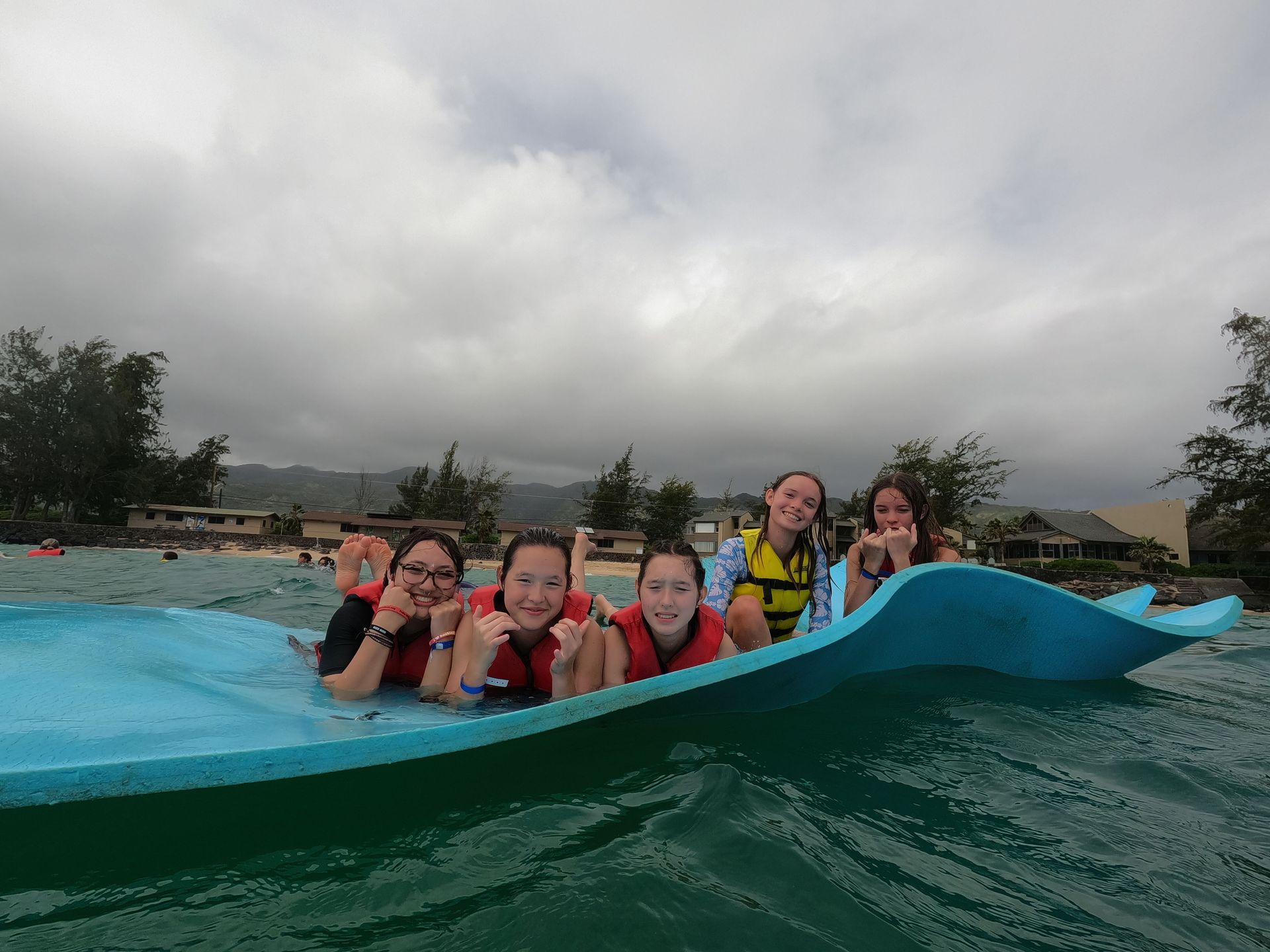 A group of people are floating on a blue raft in the water.