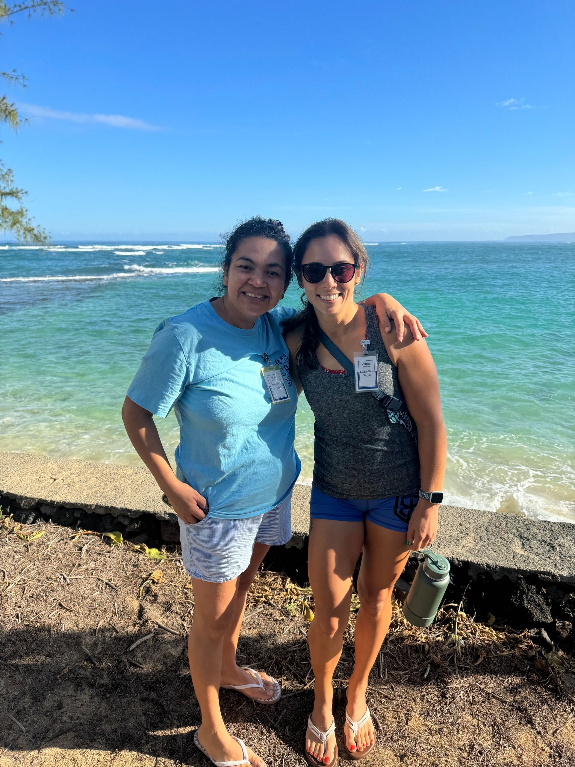 Two women are standing next to each other on a beach.