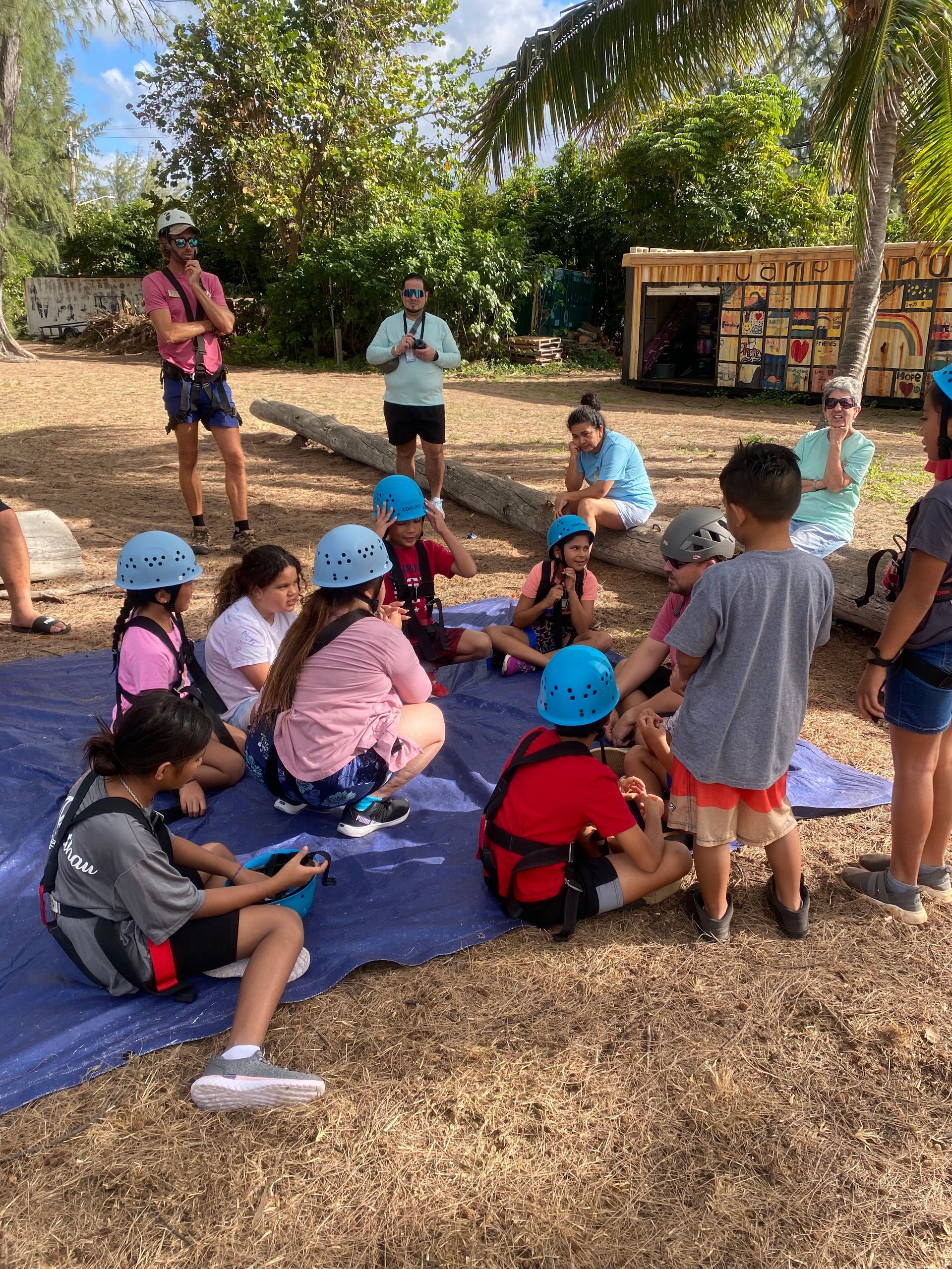 A group of children are sitting on a tarp on the ground.