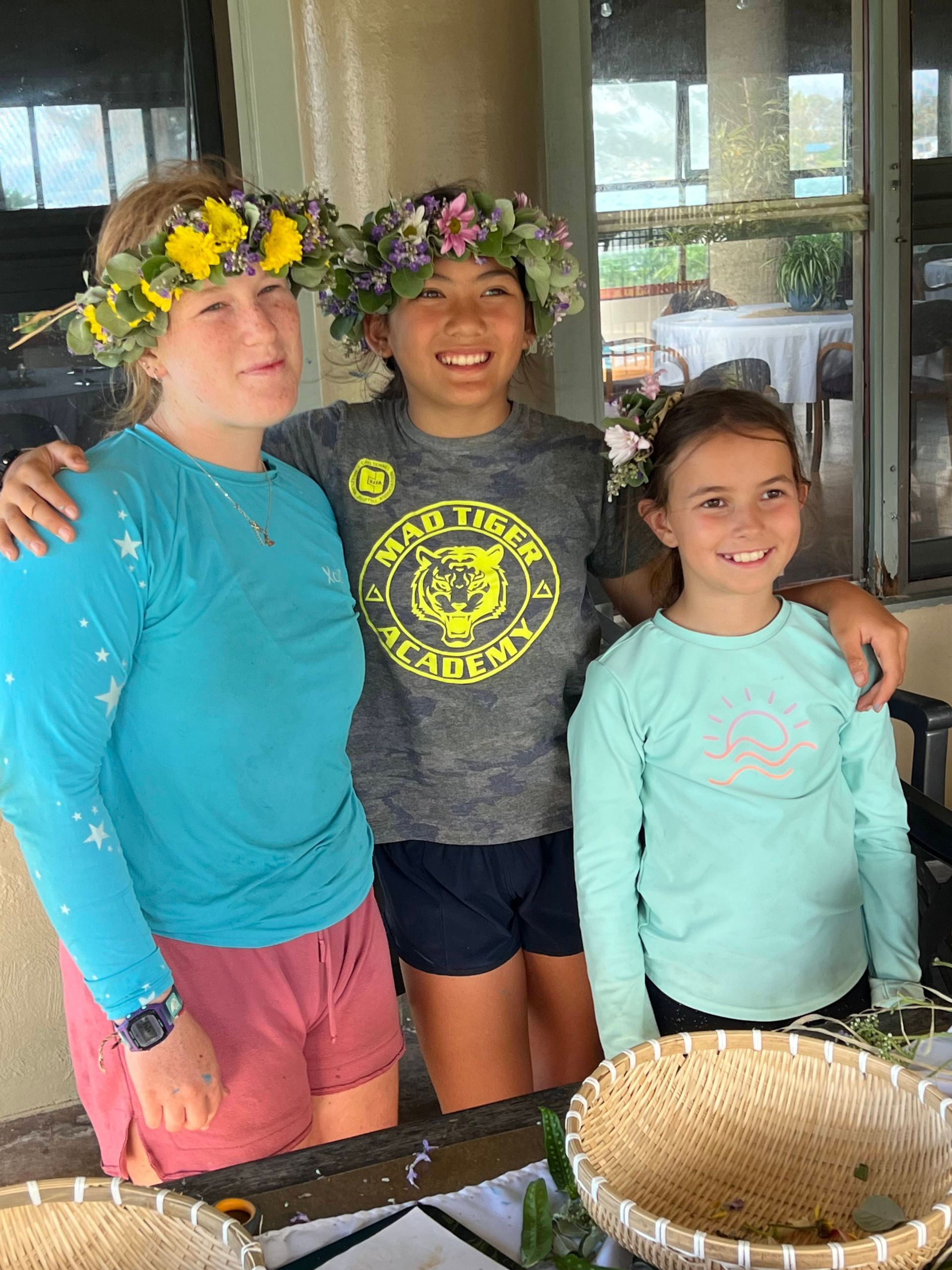 Three young girls wearing flower crowns are posing for a picture.