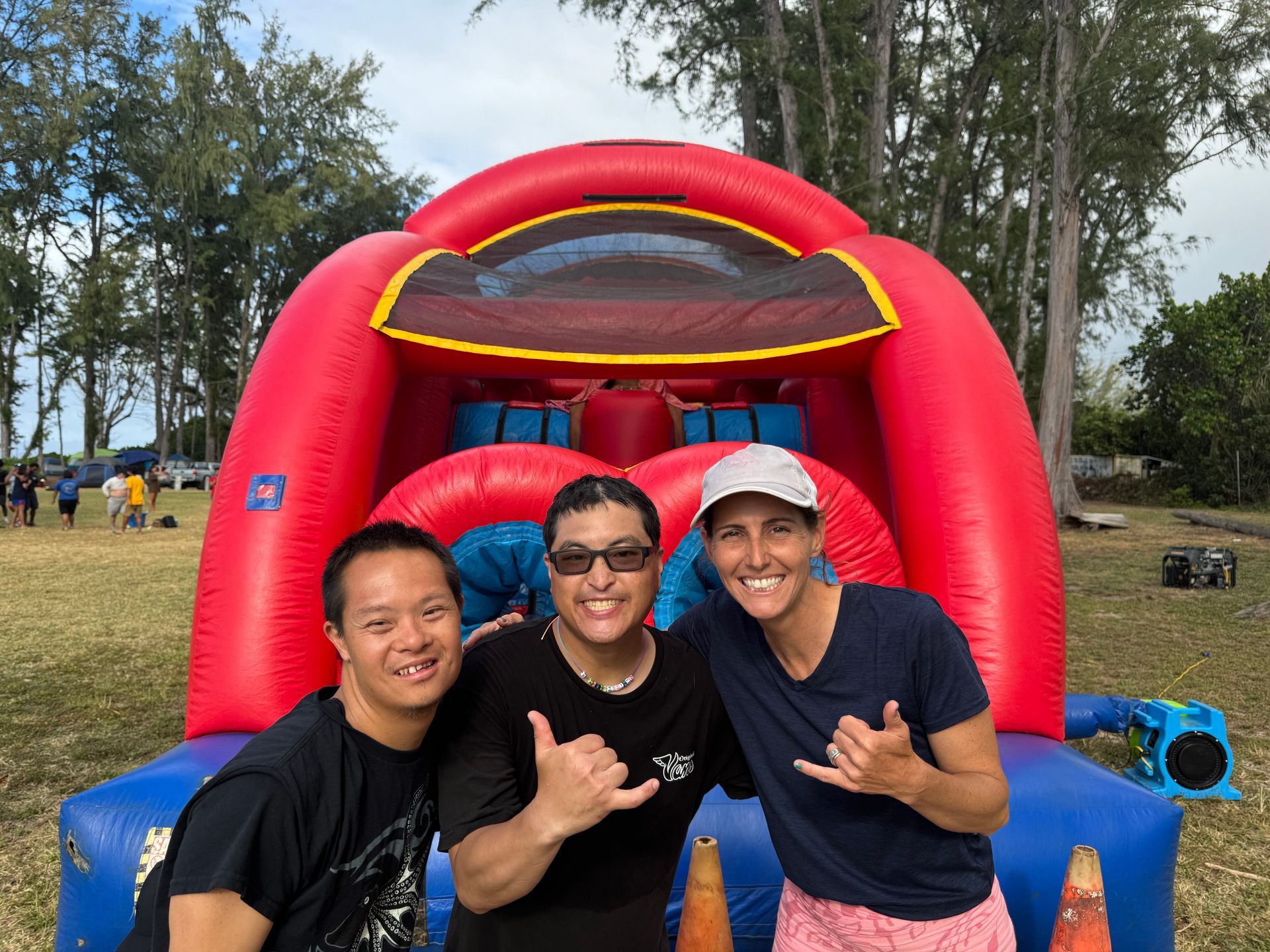 Three men are posing for a picture in front of a bouncy house.
