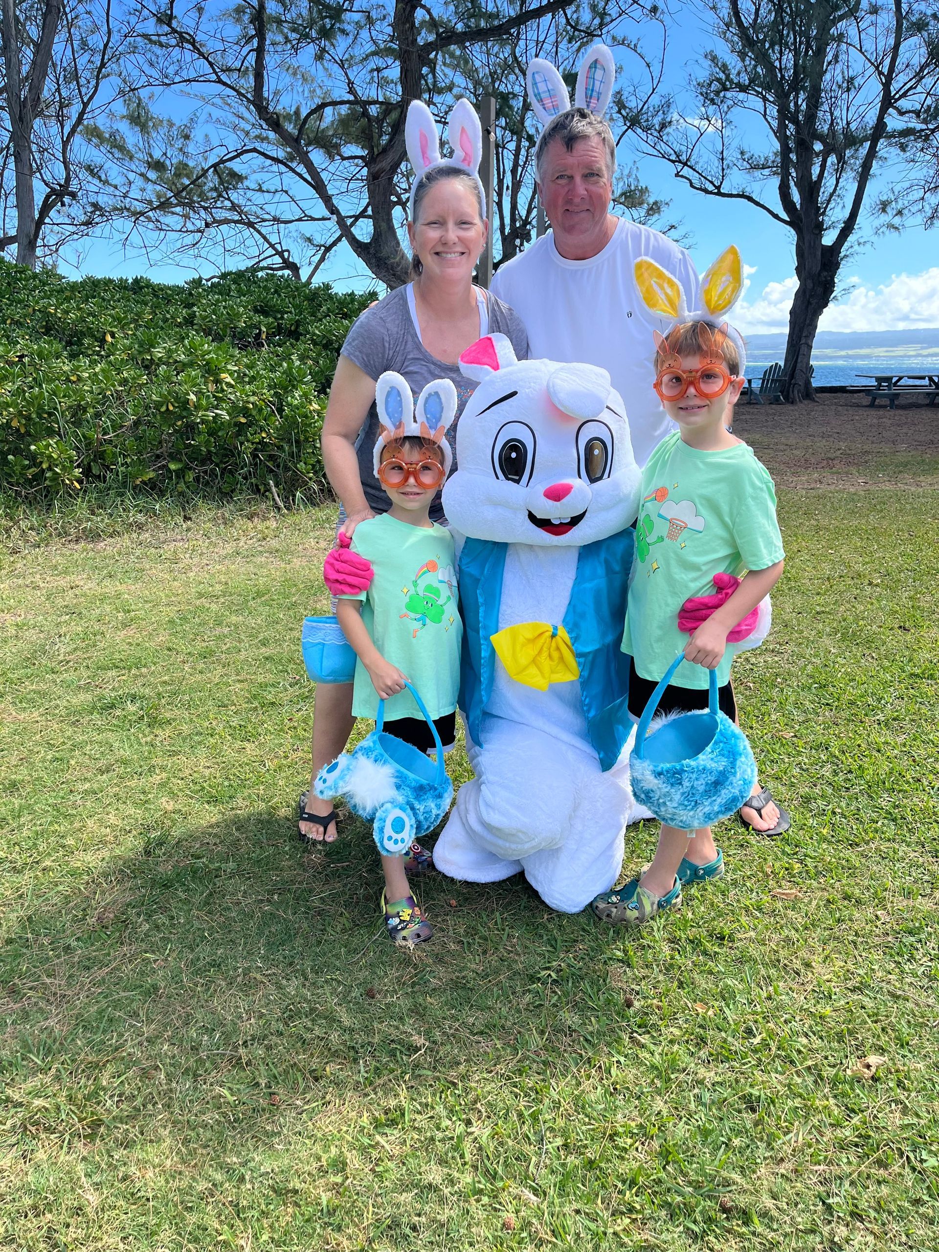 A family is posing for a picture with an easter bunny mascot.
