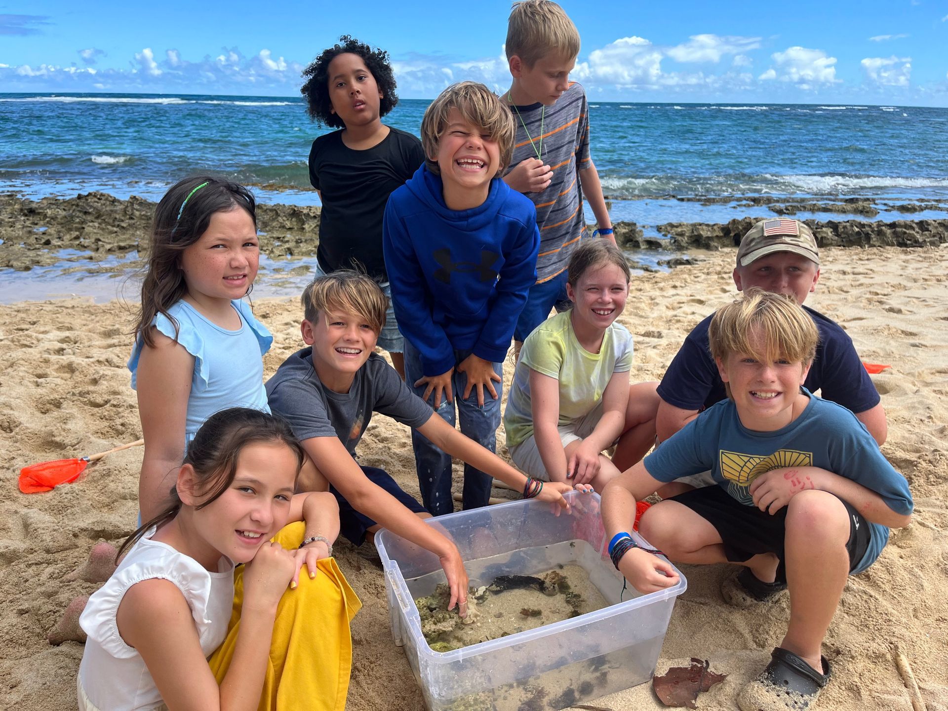 A group of children are posing for a picture on the beach.