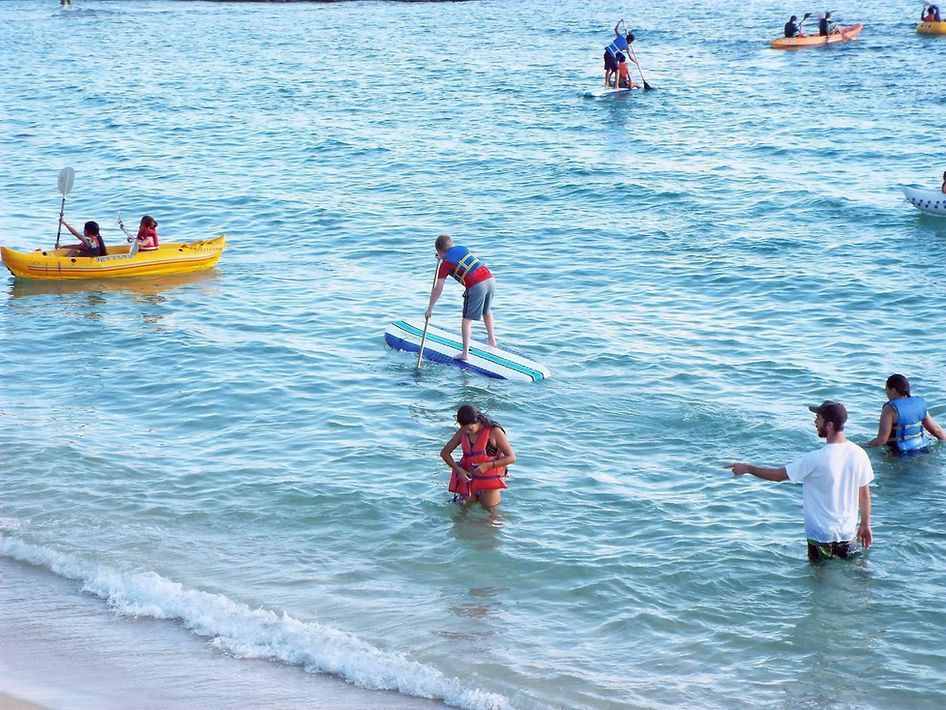 A group of people are riding kayaks and paddle boards in the ocean.