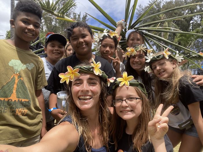 A group of children wearing flower crowns are posing for a picture.