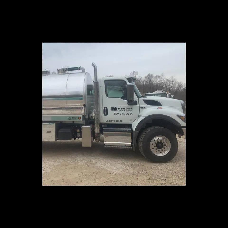 A large white truck is parked in a dirt lot.