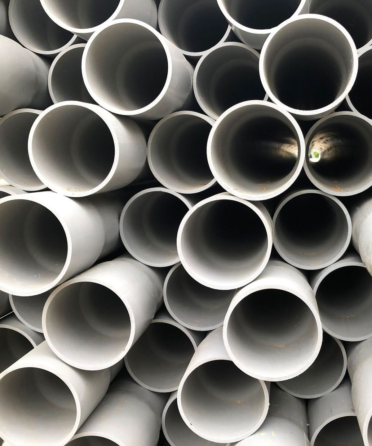 Man Inside Sewer — Kalamazoo, MI — Modern Septic & Sewer A pile of white pipes stacked on top of each other