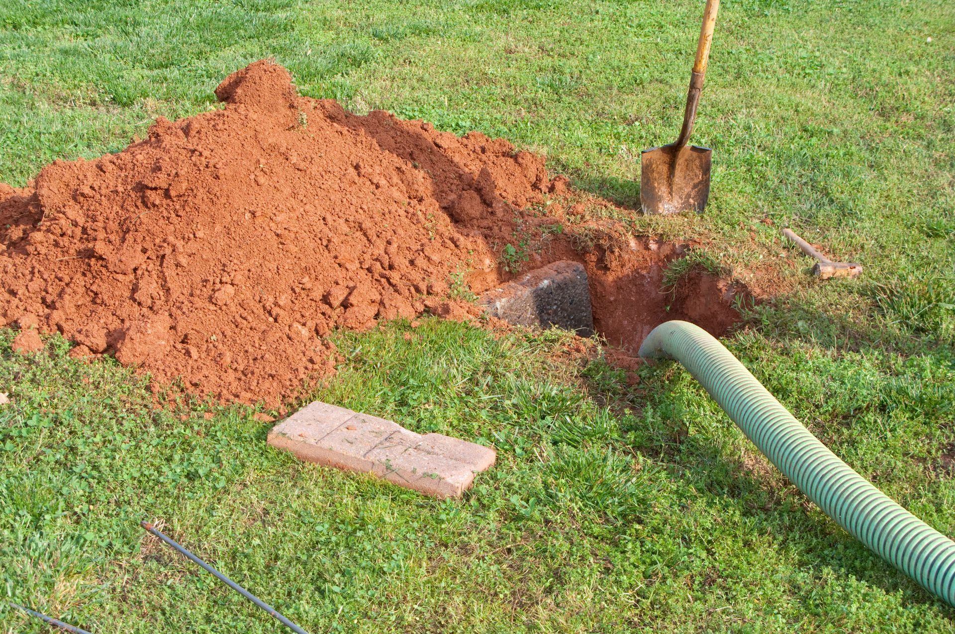 Man Inside Sewer — Kalamazoo, MI — Modern Septic & Sewer A hose is being used to pump dirt into a hole in the ground.