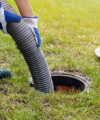 Searching For Line — Kalamazoo, MI — Modern Septic & Sewer A person is using a vacuum hose to pump sewage into a manhole.