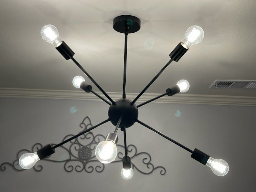 A black chandelier with many light bulbs hanging from the ceiling