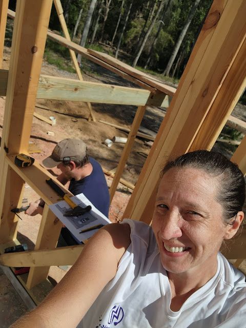A woman is taking a selfie in front of a building under construction.