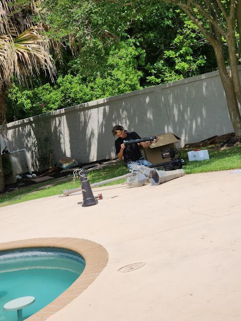 A man is sitting on the ground next to a pool.