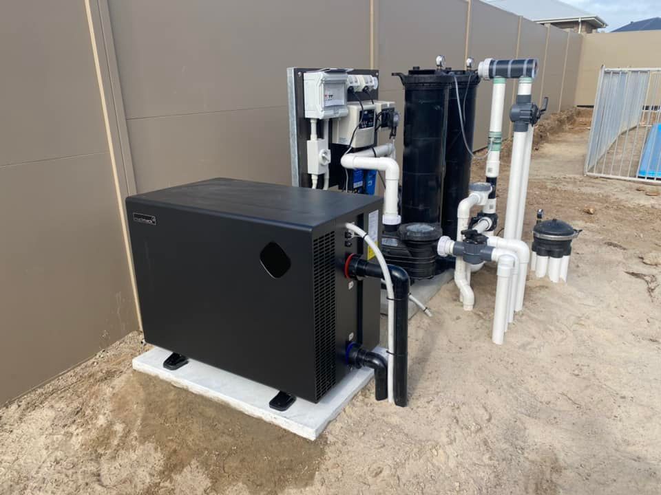 A Black Pool Heat Pump Sits on a Concrete Pad Next to Pool Filtration Equipment — Tempshift Pool Heating in Buff Point, NSW