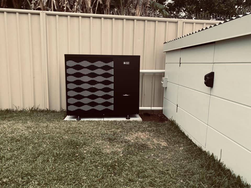 Black Pool Heater Next to a White Shed in a Grassy Backyard — Tempshift Pool Heating in Newcastle, NSW