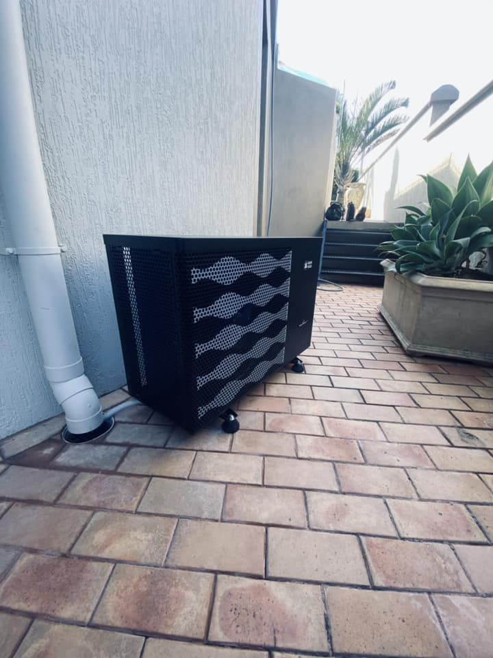 Black Pool Heater on a Brick Patio, Next to a White Wall — Tempshift Pool Heating in Newcastle, NSW
