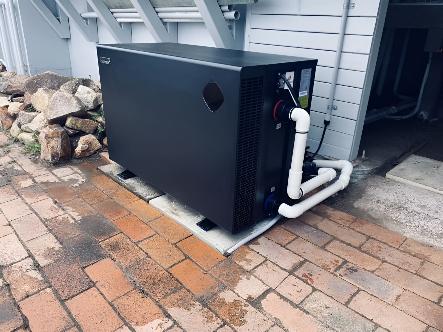 Black Pool Heat Pump on a Concrete Pad, With White Pipes, Set on Brick Patio — Tempshift Pool Heating in Buff Point, NSW