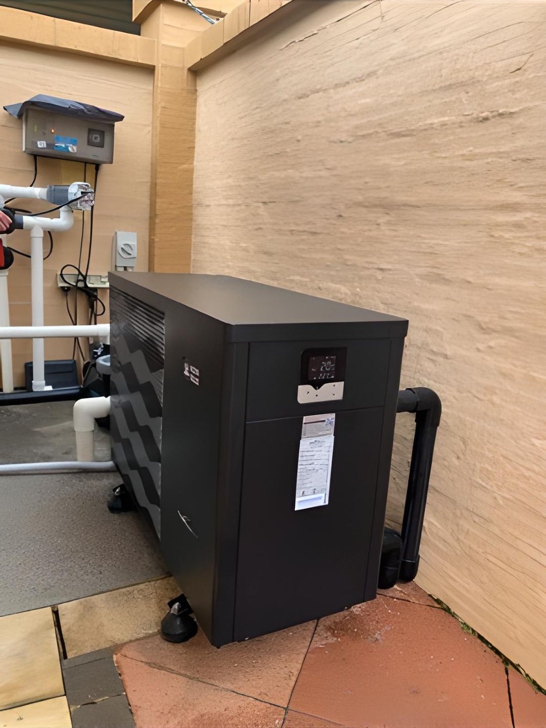 A Dark-Colored Pool Heater Next to a Beige Wall — Tempshift Pool Heating in Buff Point, NSW