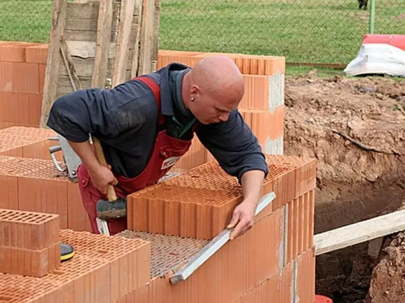 Ruwbouwfase van een woning met stevige funderingen en constructie in aanbouw.