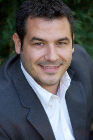 A woman with gray hair and a red shirt is smiling for the camera.