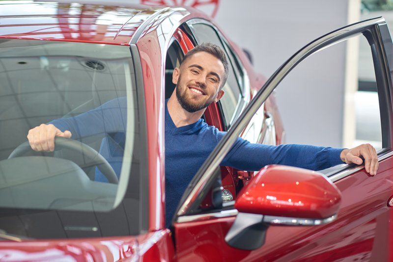 Young Man Sitting in Red Car — Fort Wayne, IN — Lederman Insurance, Inc.
