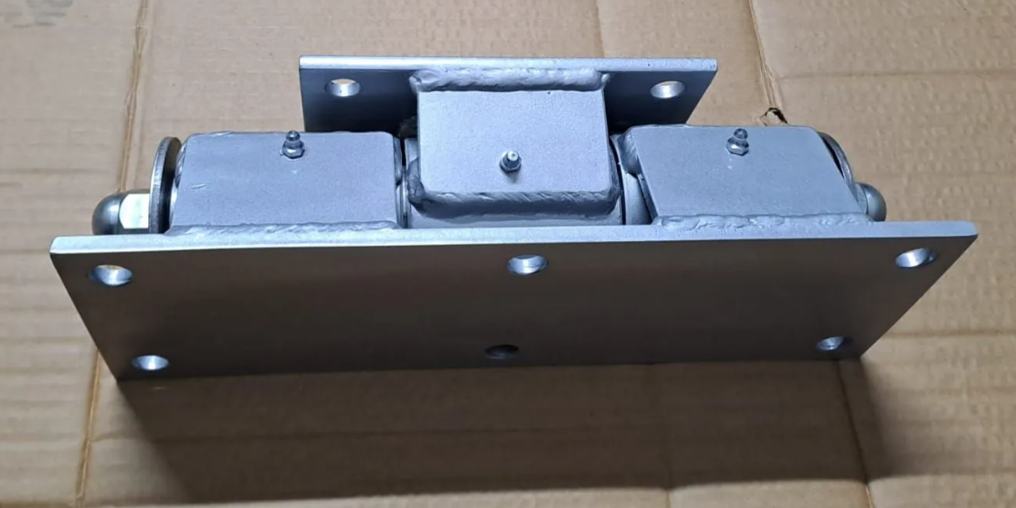 Componente industriale in metallo con piastre di montaggio imbullonate.