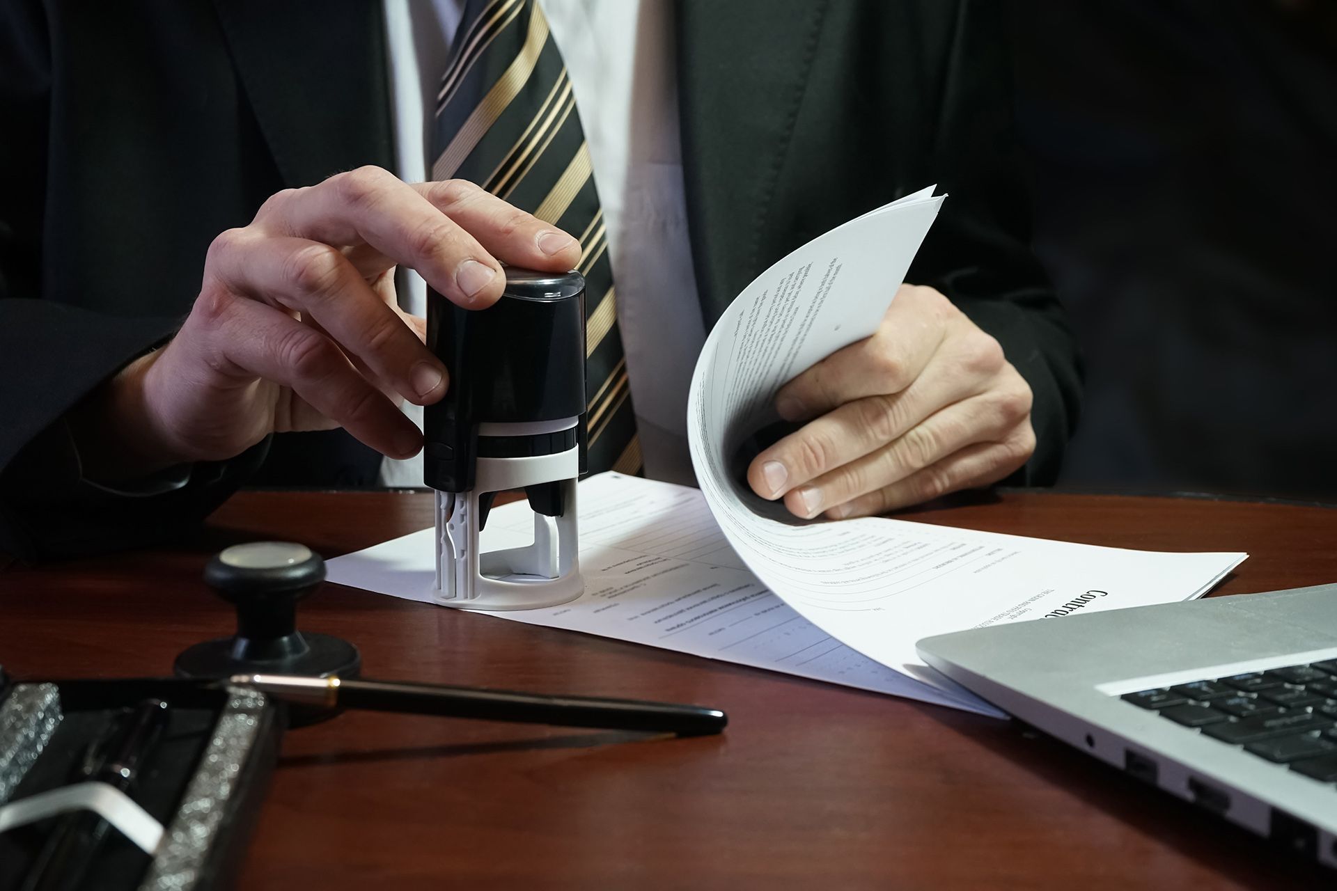 Un hombre con traje y corbata está poniendo un sello en un trozo de papel.