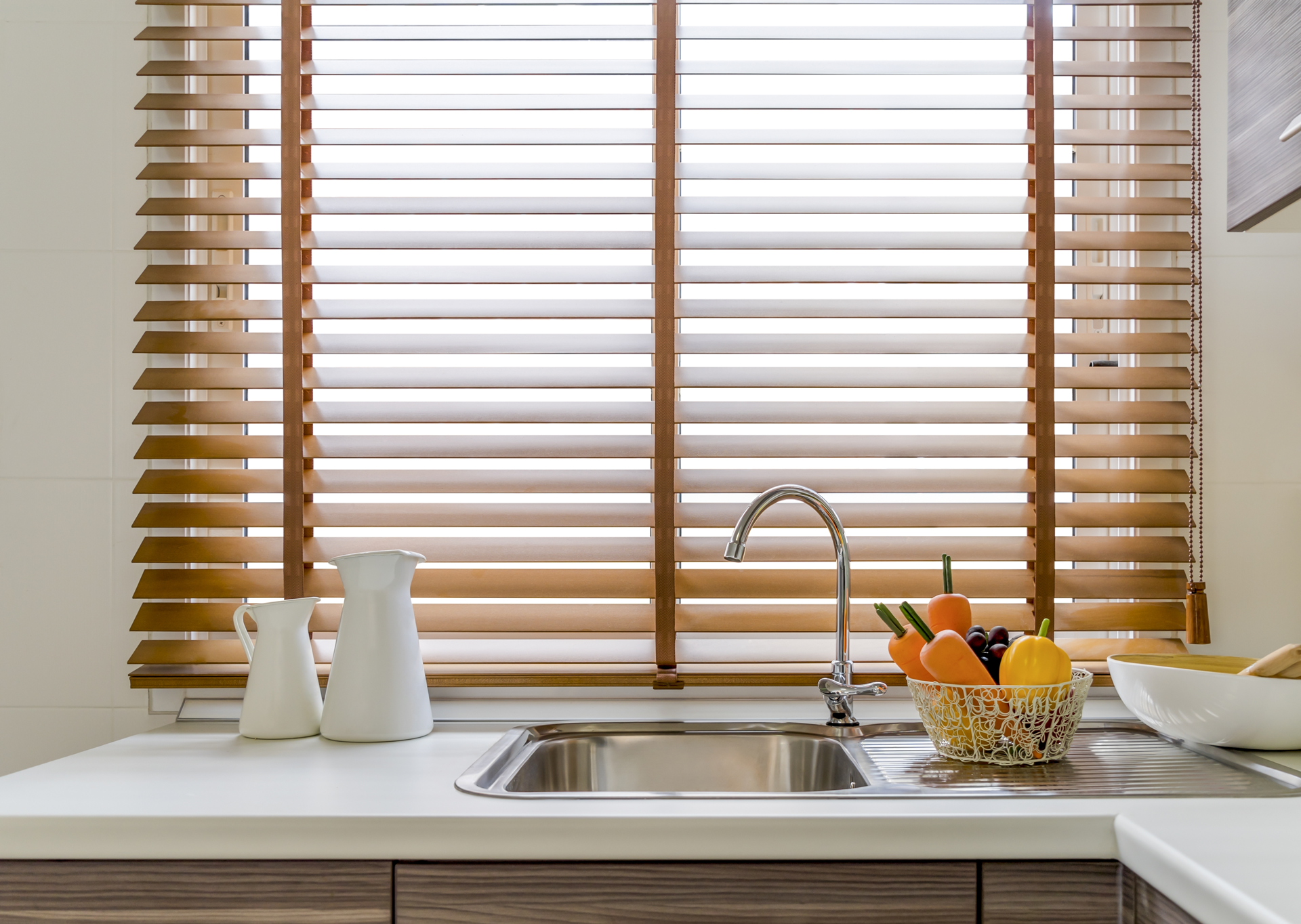A kitchen with a sink and wooden blinds on the window