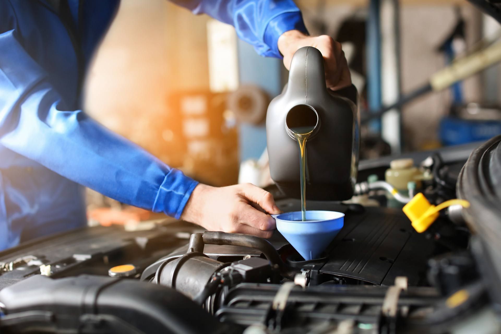 Male mechanic refilling car oil in a service center. Male mechanic refilling car oil in a service center.