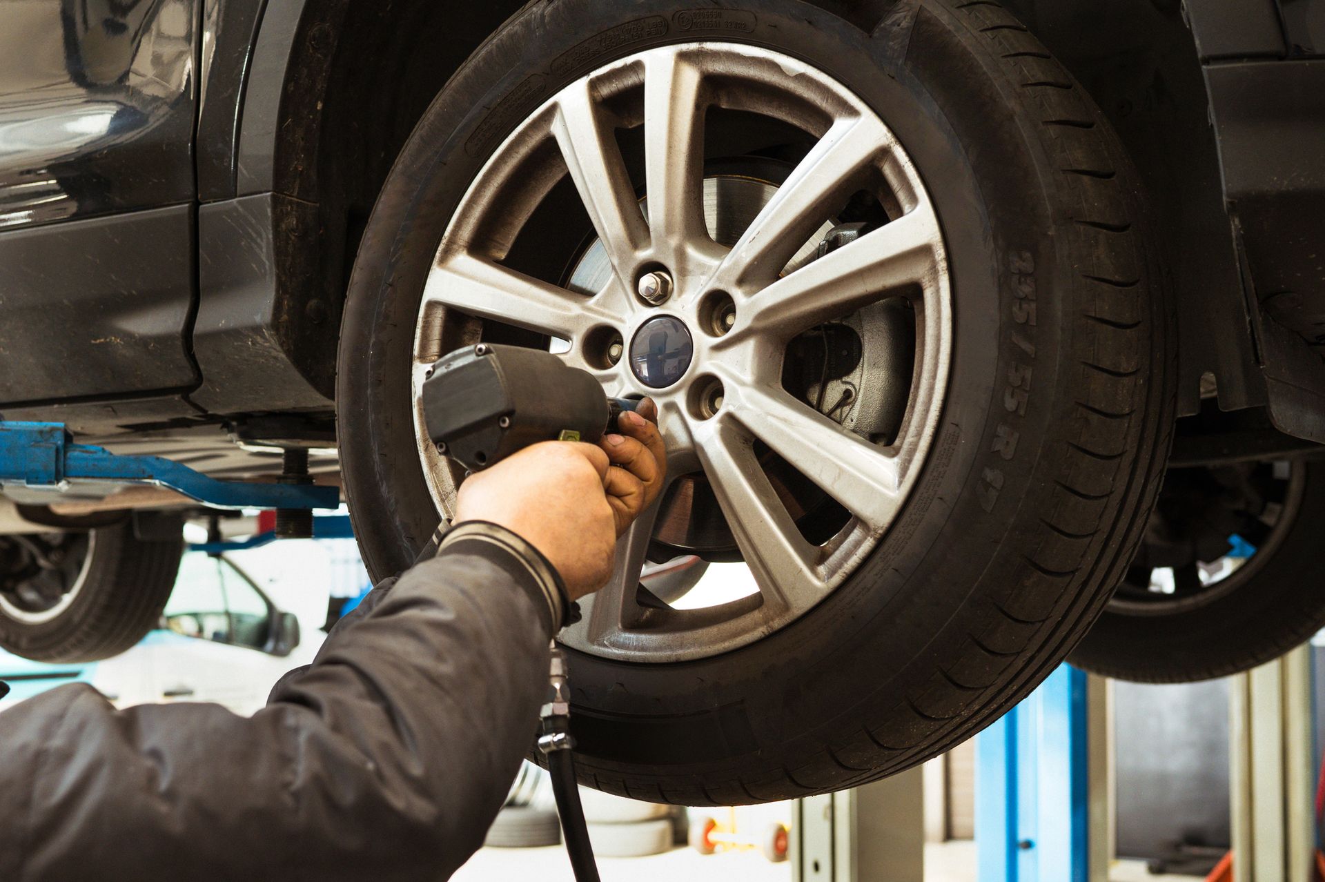 A mechanic using an impact wrench to change a car wheel in a professional garage.