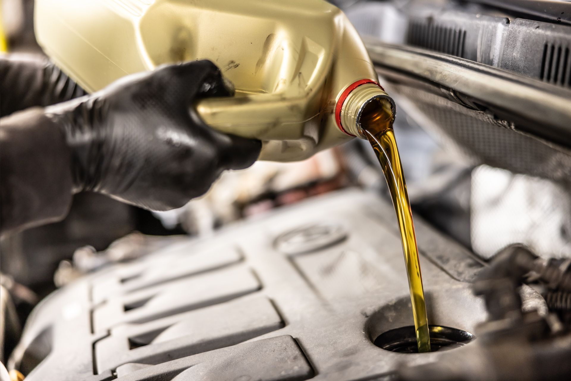 Mechanic pouring oil to car engine.
