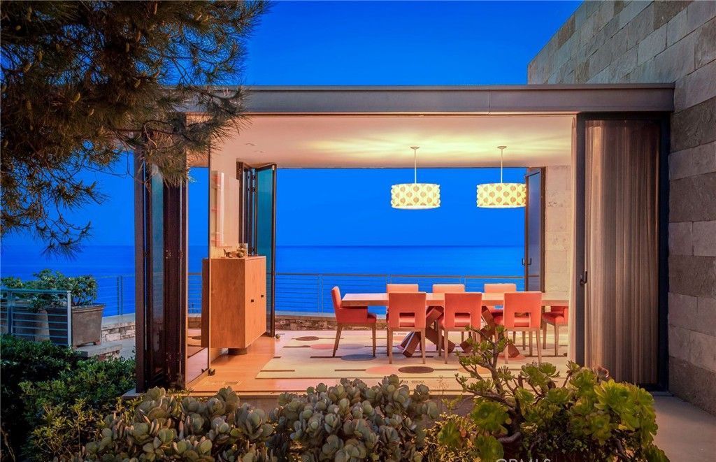 A dining room with a table and chairs overlooking the ocean