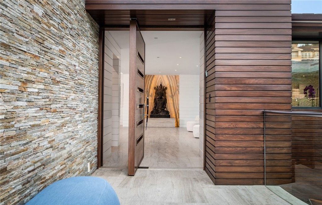 A modern house with a wooden door and a stone wall.